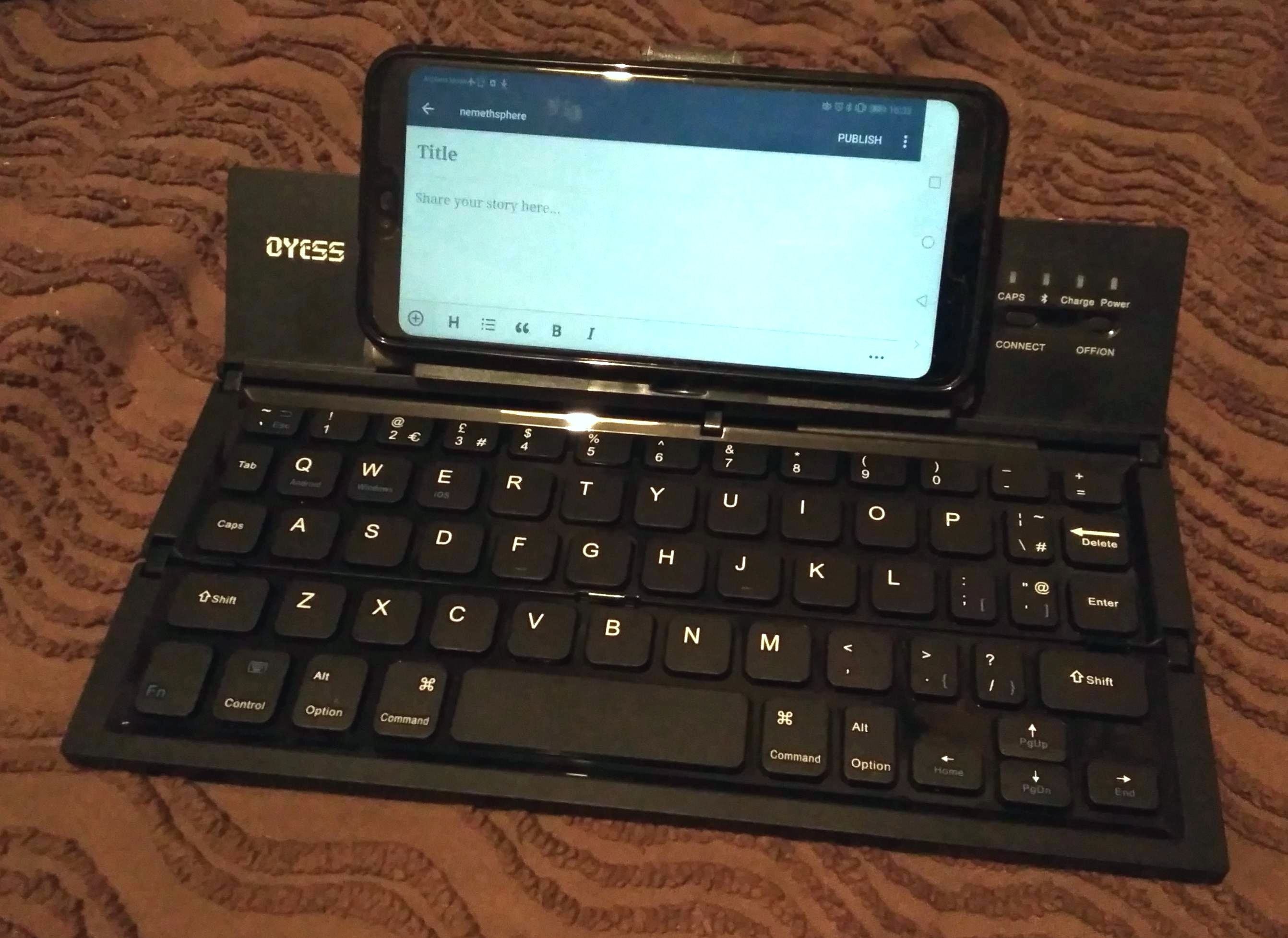The Oyess folding Bluetooth keyboard, with my phone (in its case) on the built-in stand.